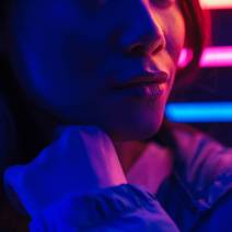 Cropped image of a beautiful young asian woman with long dark hair standing infront of a neon wall